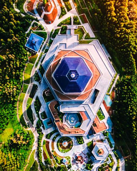 00030-187391636-vertical perspective aerial photography, unique_architecture, building, geometric_design, surrounded_by_trees, nature, landscape.png